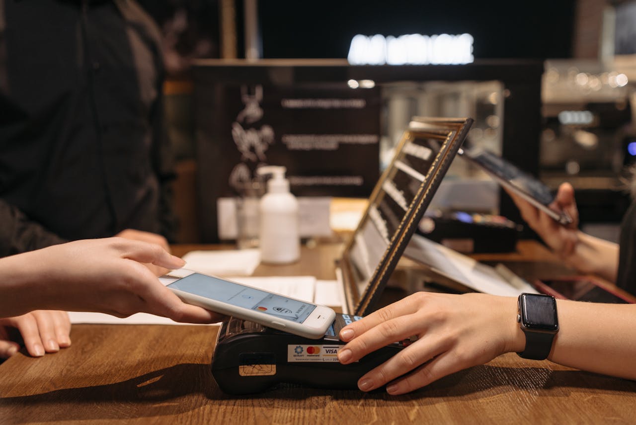 heros-img Hands using mobile for contactless payment at café terminal.